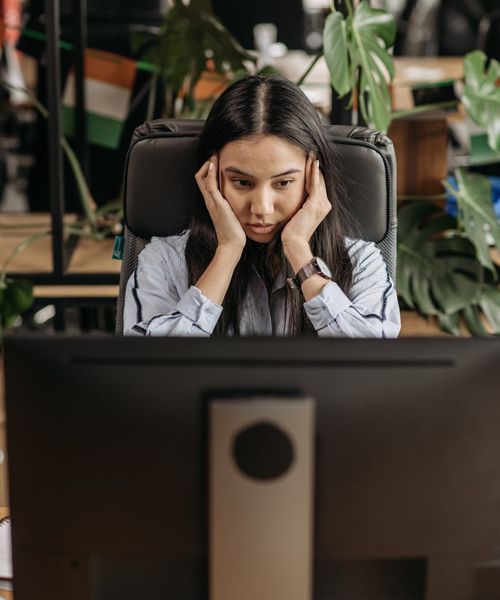 Person working at a computer desk with a hint of fatigue in their posture.
